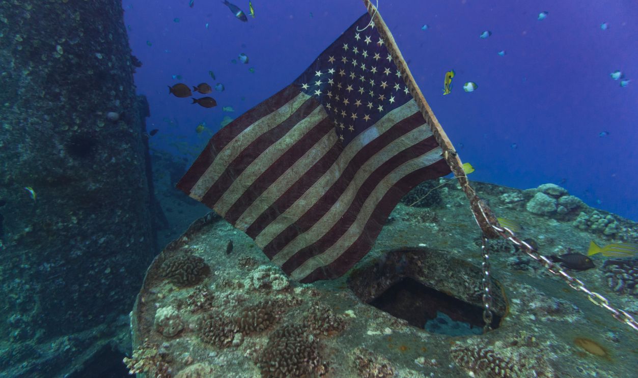 An American flag waves gently in the current aboard the YO-257 wreck off the coast of Oahu, Hawaii.