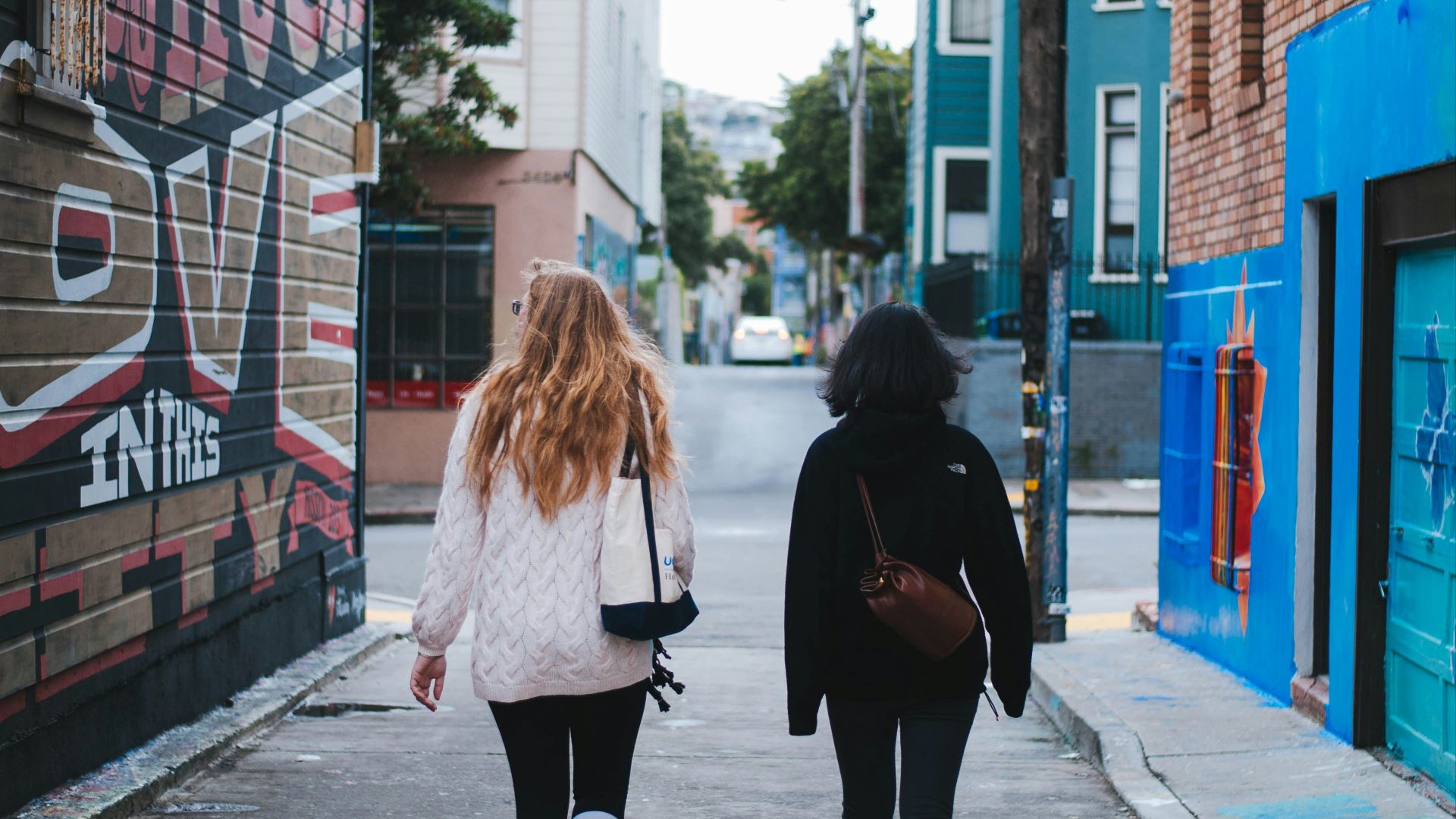 two women in sweaters walking on street