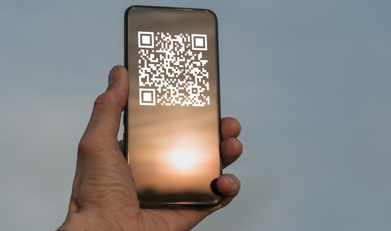 A man holds a smartphone with a QR code image