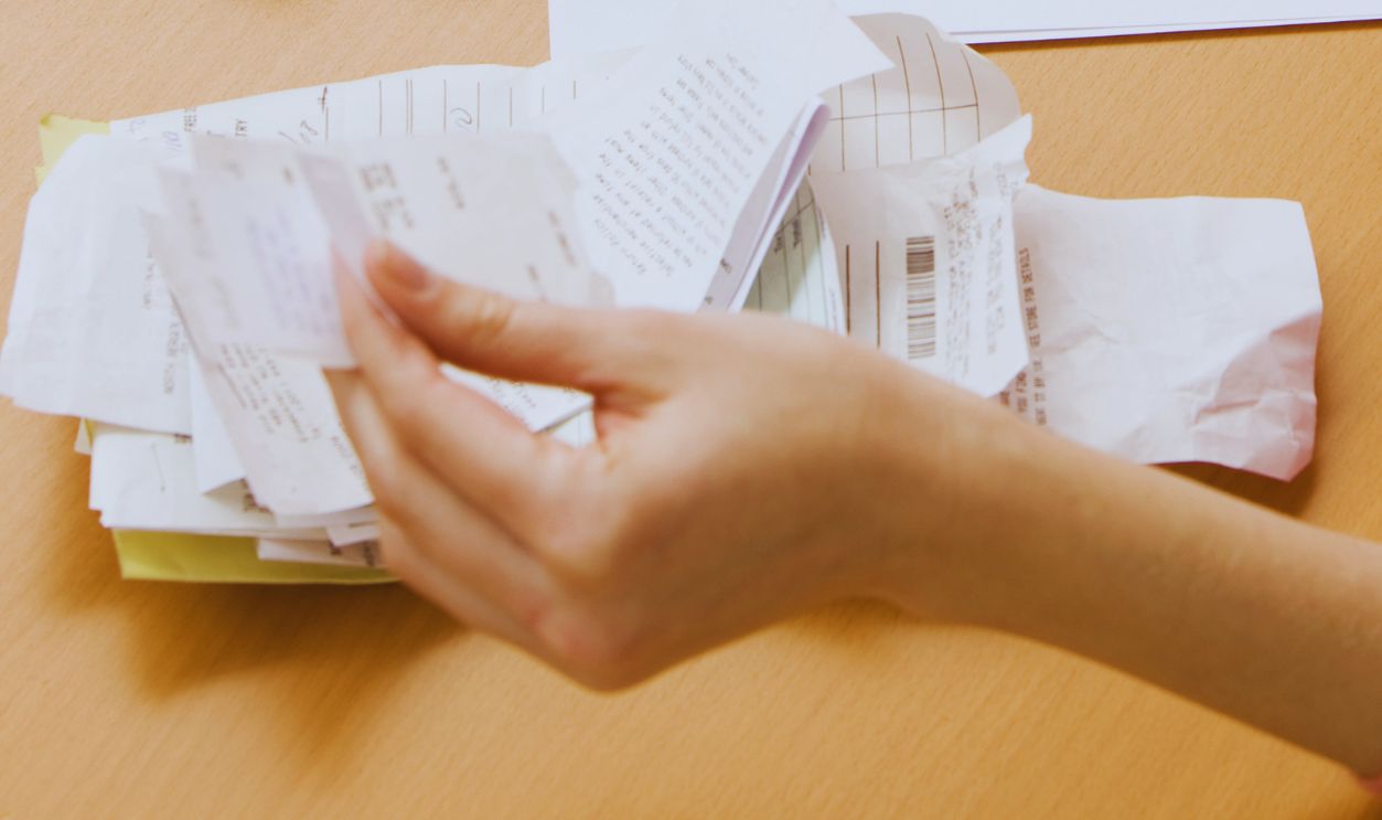 A young woman looks upset while sorting through her old receipts. Horizontal shot.