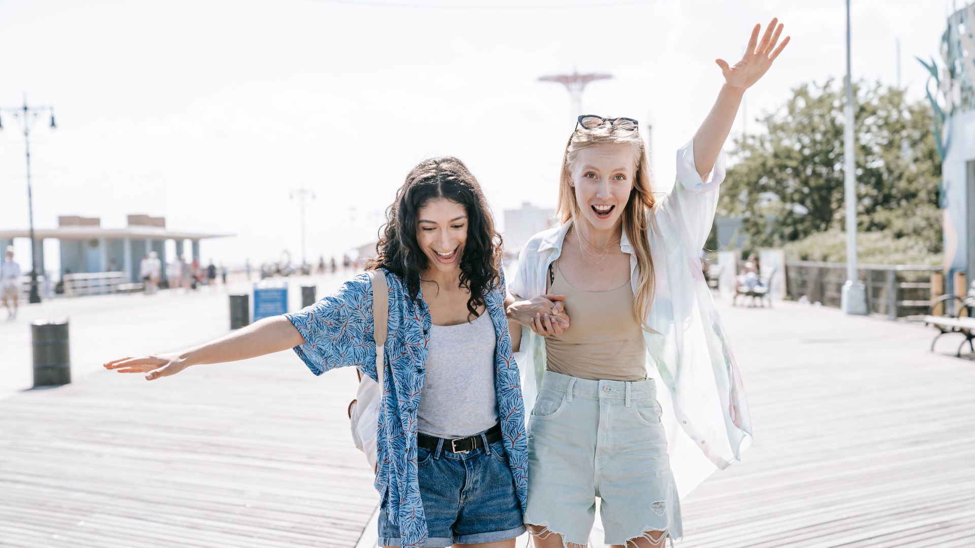 Two women having fun on a sunny boardwalk, embracing friendship and summer vibes.