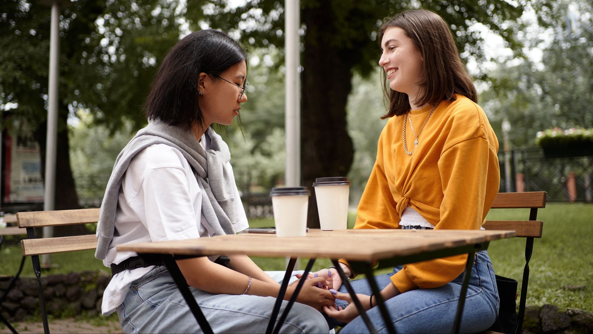 A loving interracial couple holding hands and enjoying a heartfelt conversation at an outdoor cafe.