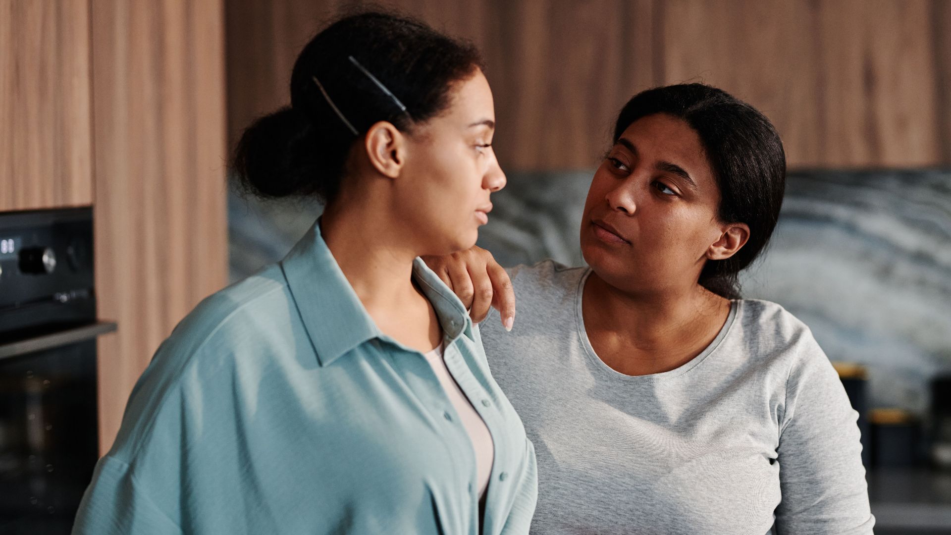 Two women sharing a supportive moment indoors, highlighting friendship and connection.