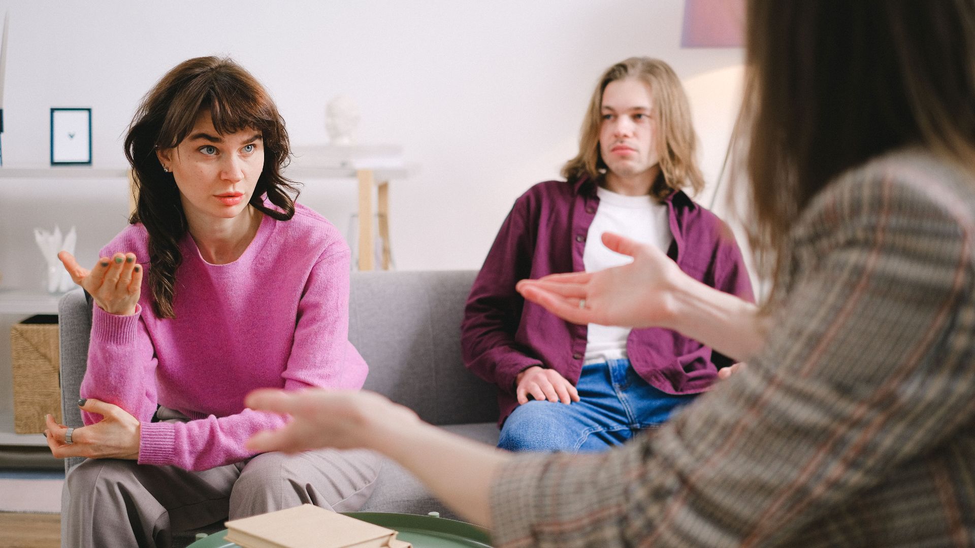 Couple actively participates in a therapy session with a counselor indoors.