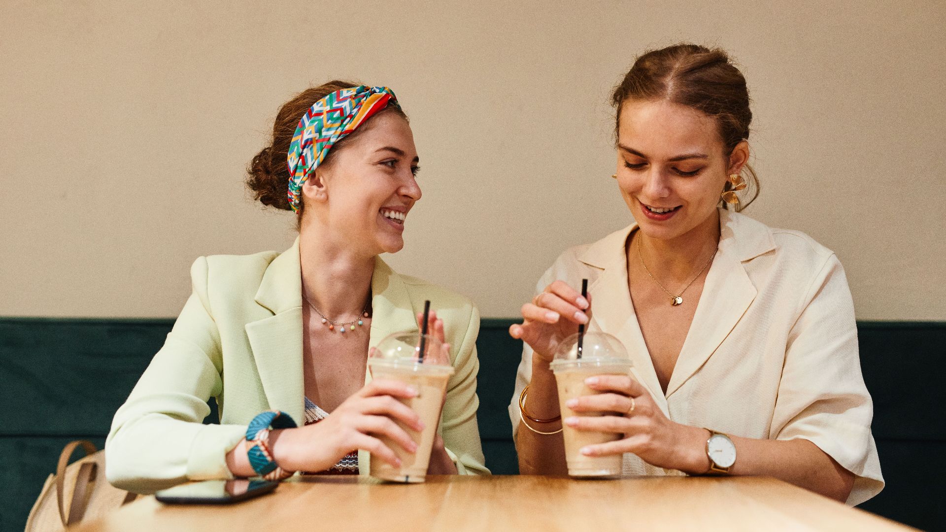 Two young women having a lively conversation over iced coffee at a café.