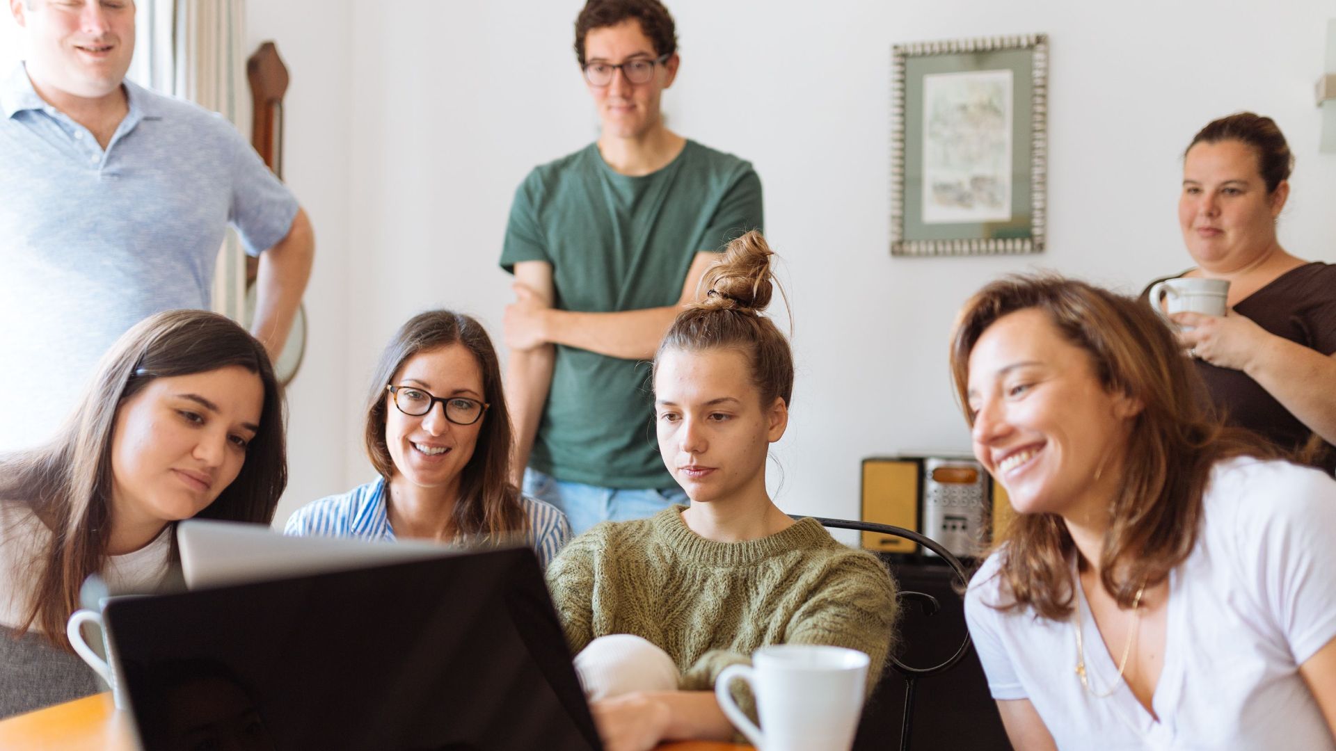 A diverse group of adults at work, enjoying a casual meeting indoors with focus and smiles.
