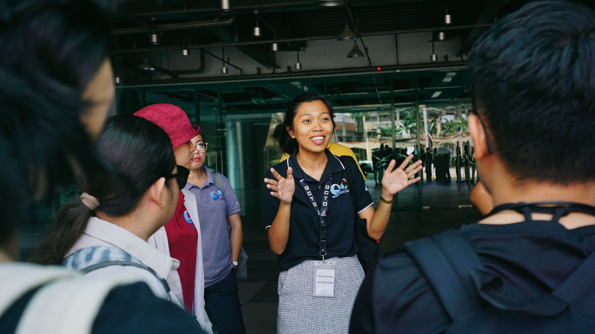 Tour guide leading a group tour, engaging visitors with gestures in an outdoor urban setting.