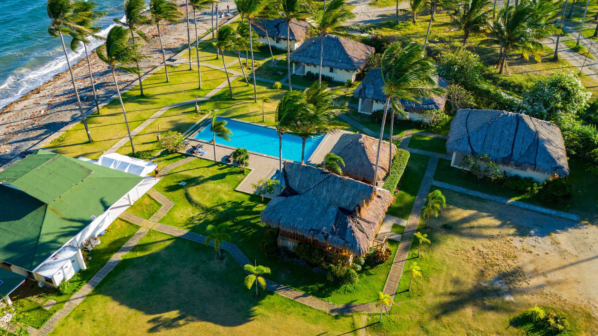 Stunning aerial view of a tropical resort in Bacong, Philippines, showcasing palm trees, beach, and swimming pool.