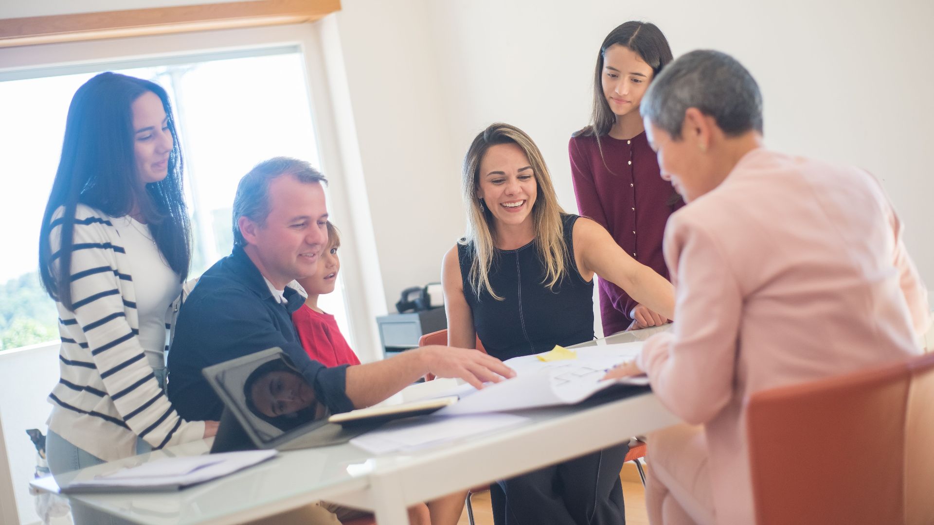 A happy family gathering around a desk during a home meeting, discussing documents.