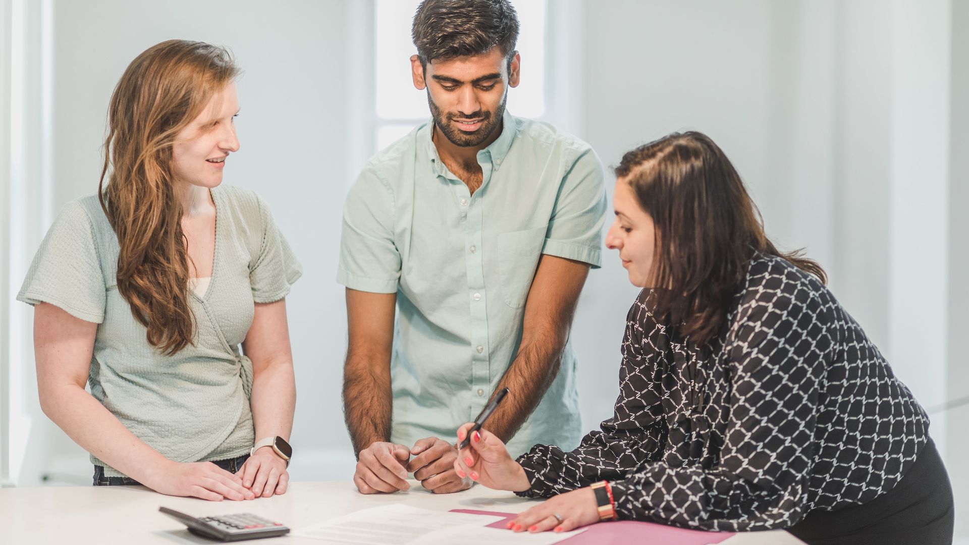 Three professionals engaged in a discussion indoors, possibly real estate related.