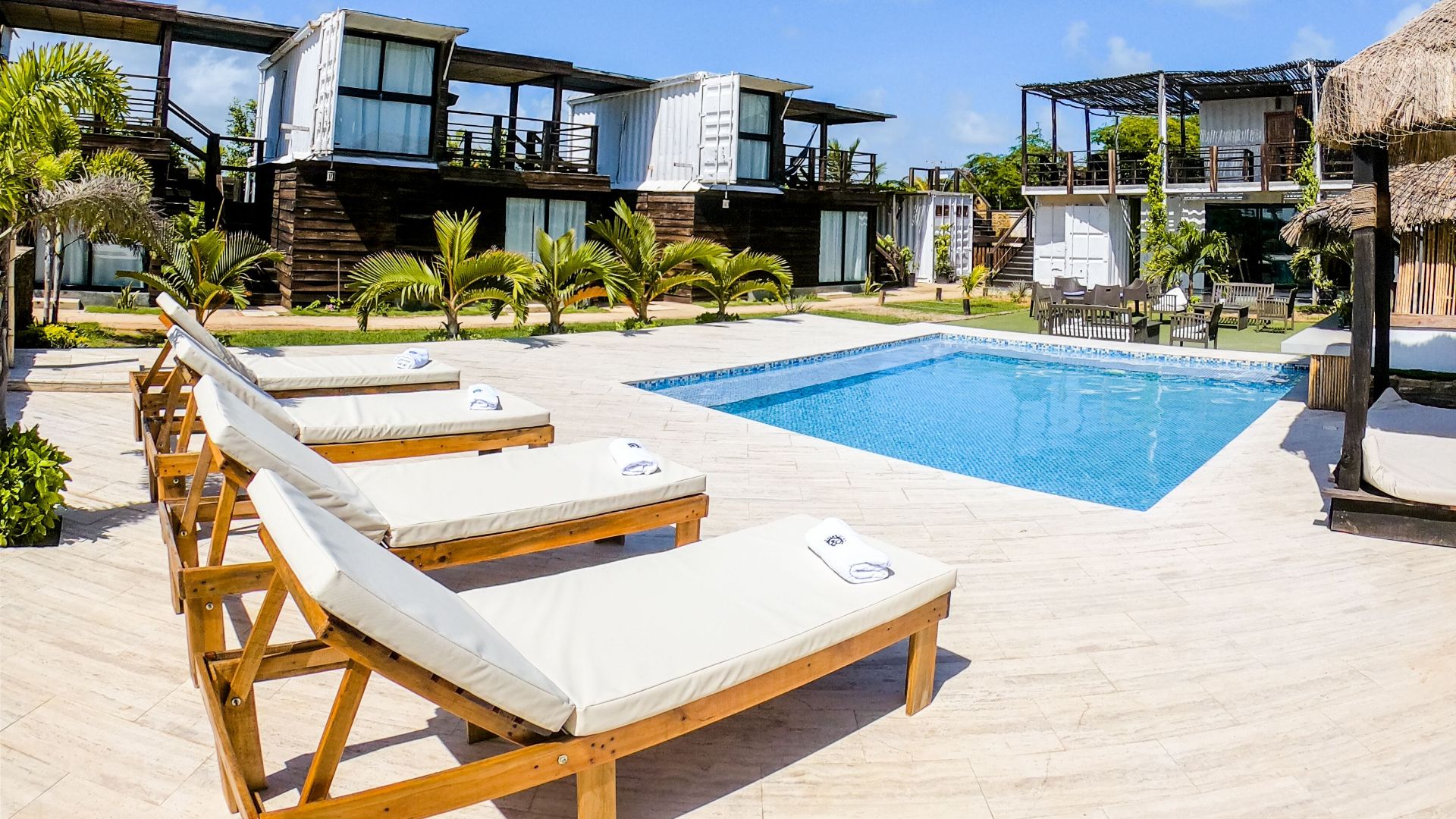 Serene resort pool area with chaise lounges under a clear blue sky, ideal for relaxation.