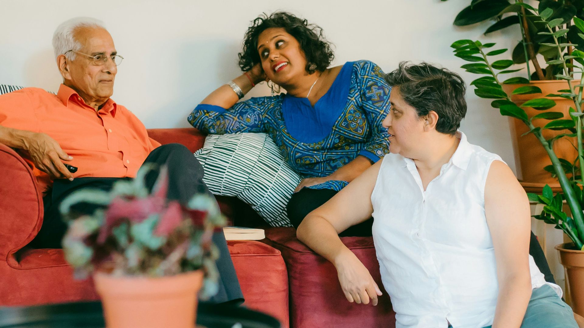 a woman sitting on top of a red couch next to a man