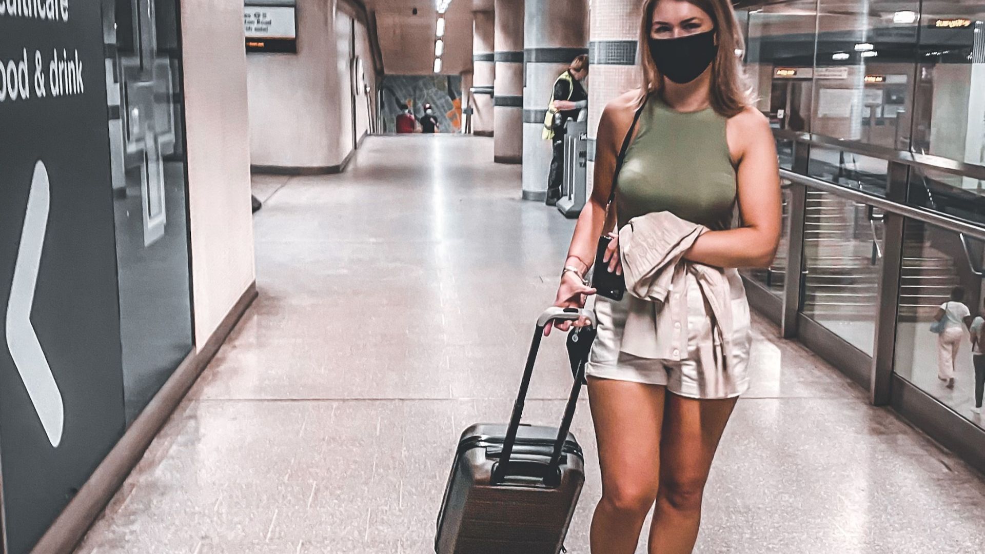 A woman in an airport terminal with a suitcase, ready for travel.