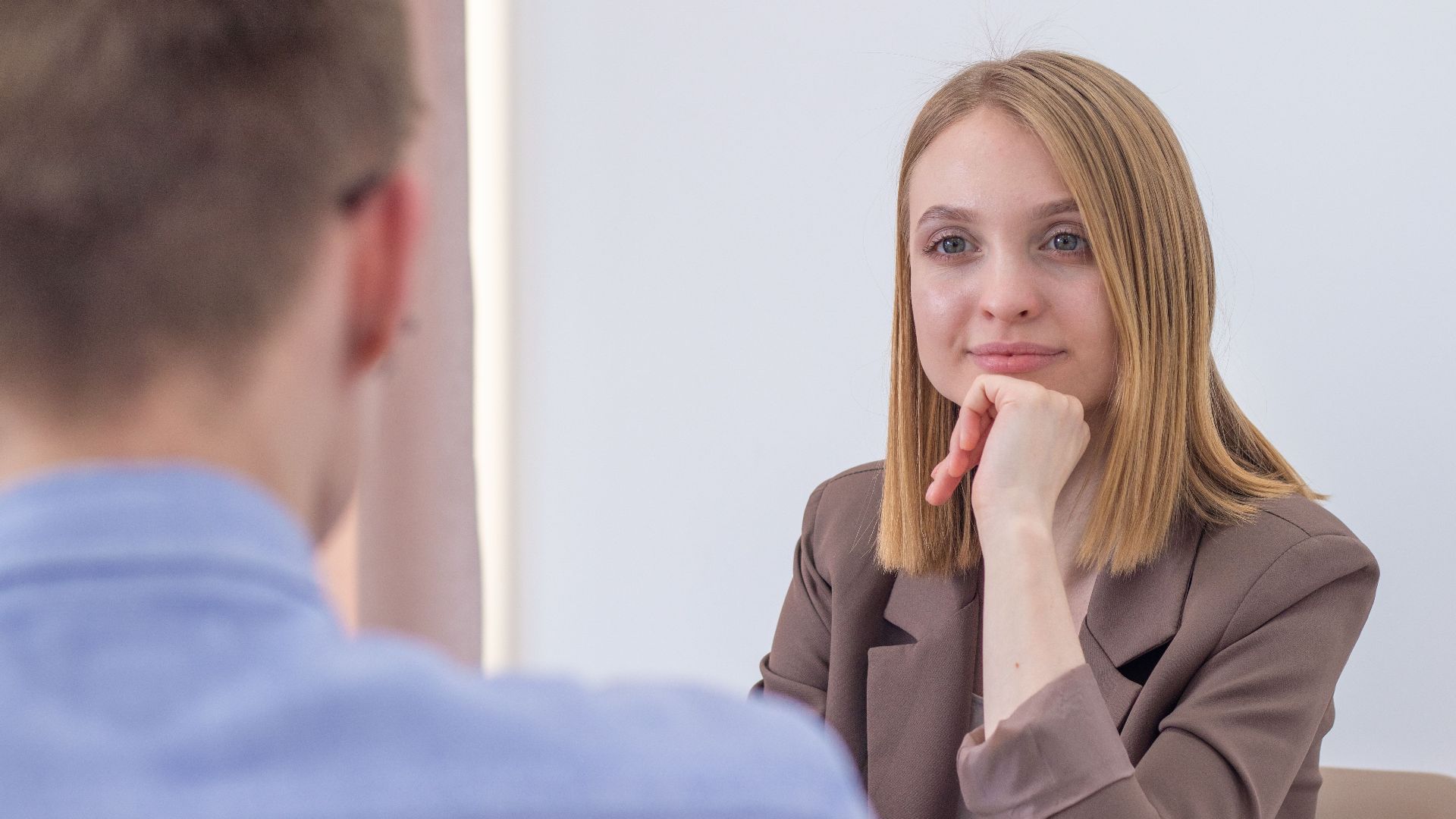 Confident businesswoman attentively listening during an office meeting, hand on chin, thoughtful expression.