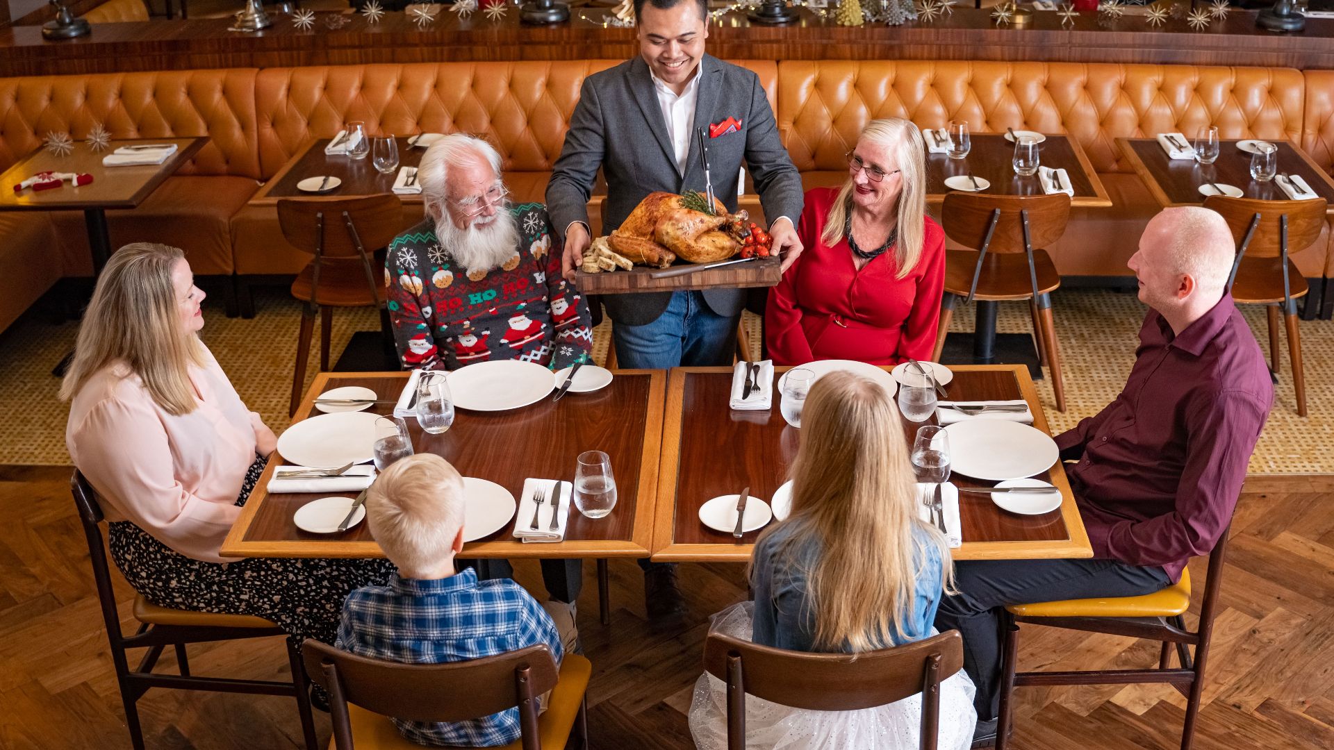 A family gathers in a Dubai restaurant for a festive holiday meal with turkey.