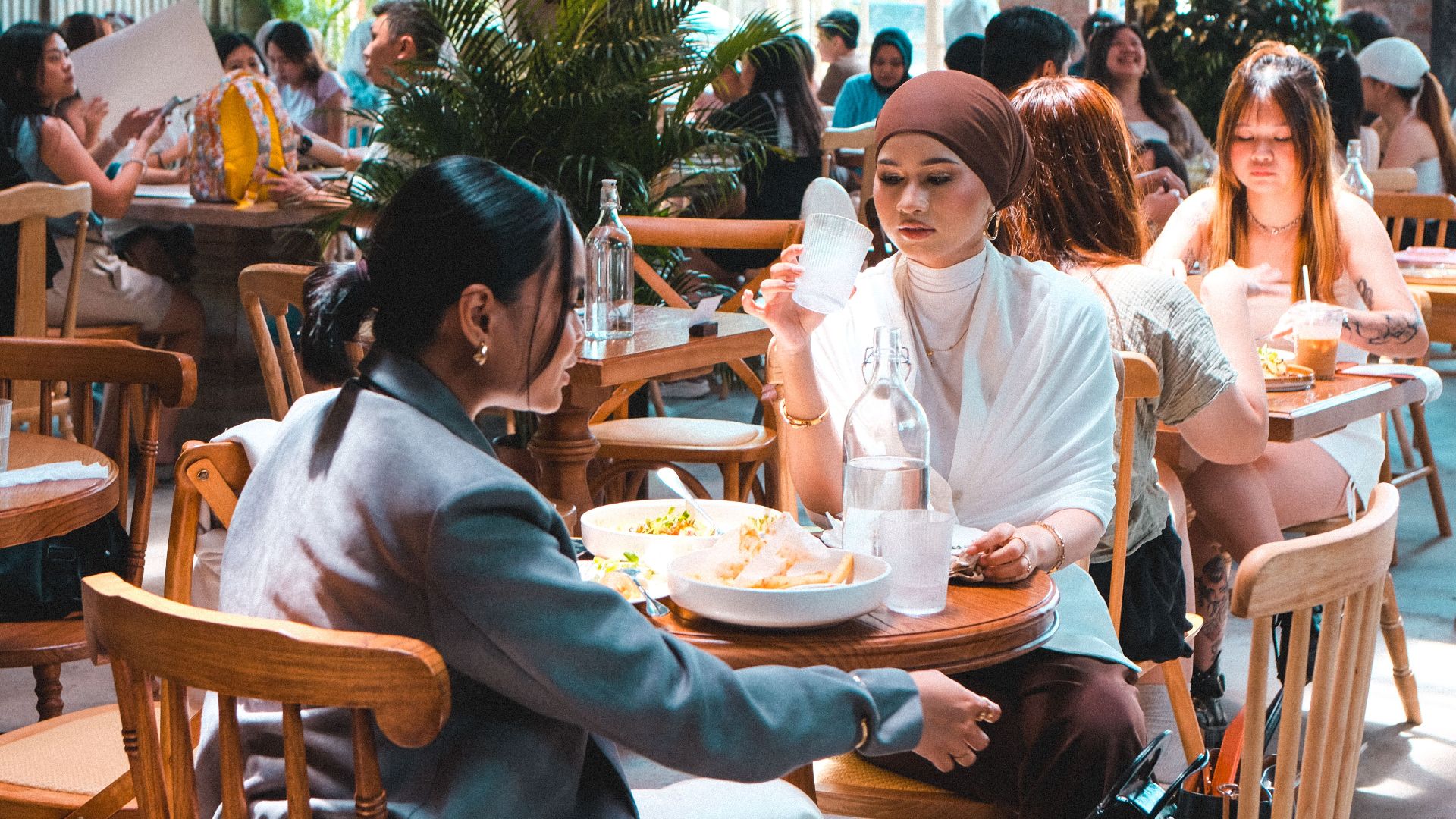 Capture of a bustling café scene in Kuala Lumpur, showcasing diverse interactions and vibrant dining atmosphere.