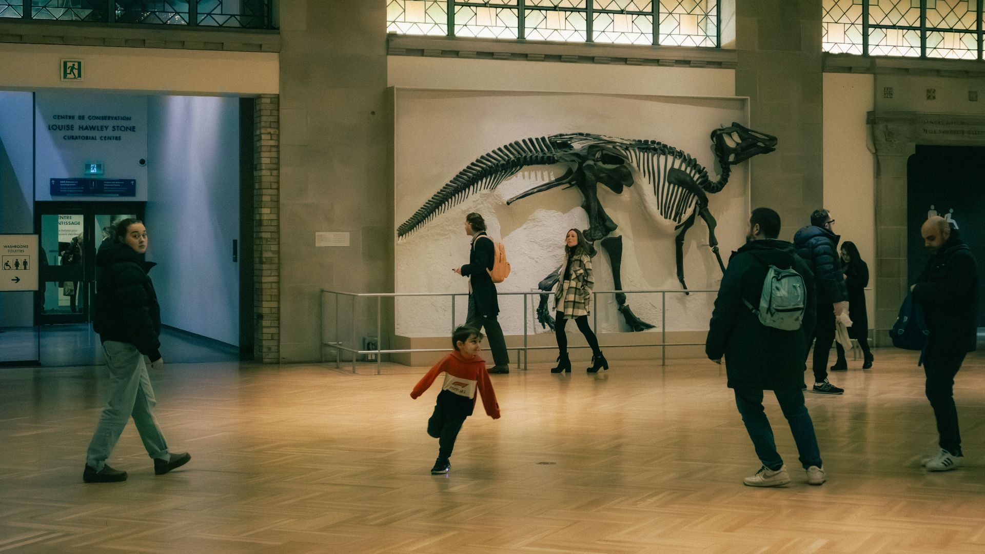 People exploring a dinosaur exhibit inside a Toronto museum, showcasing fossils and history.