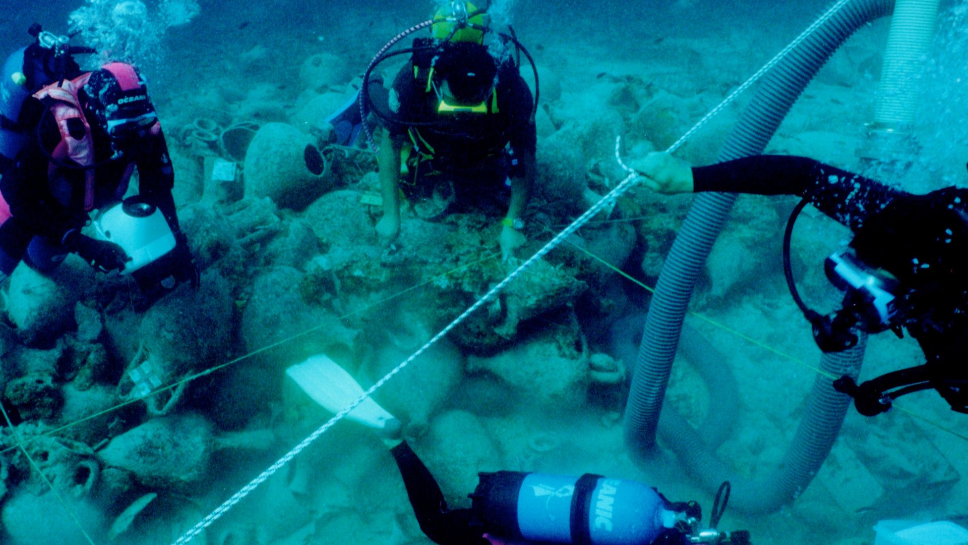 Diving archaeologists excavating the Alonnisos shipwreck in fall 2000, trench Θ3. The 2x2 m rope grid and airlift are visible.