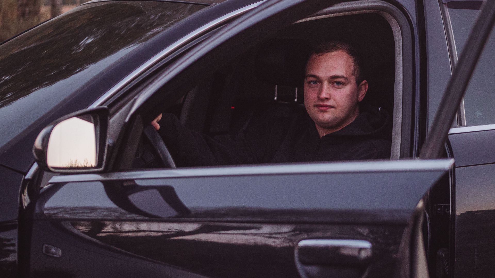 Male driver in a parked car during twilight, capturing a serene moment.