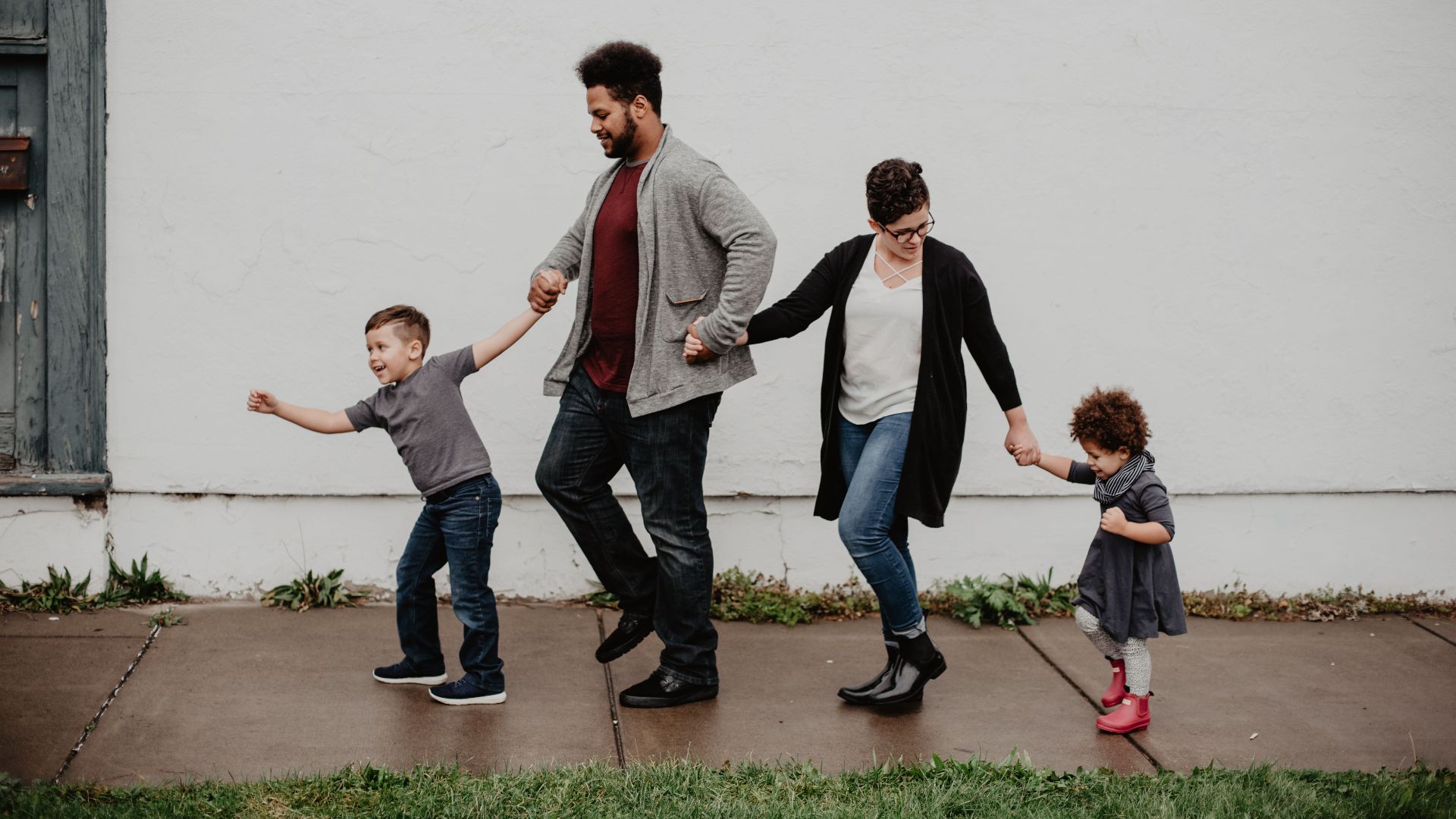 A joyful family walking together outdoors, holding hands in a playful and happy moment.