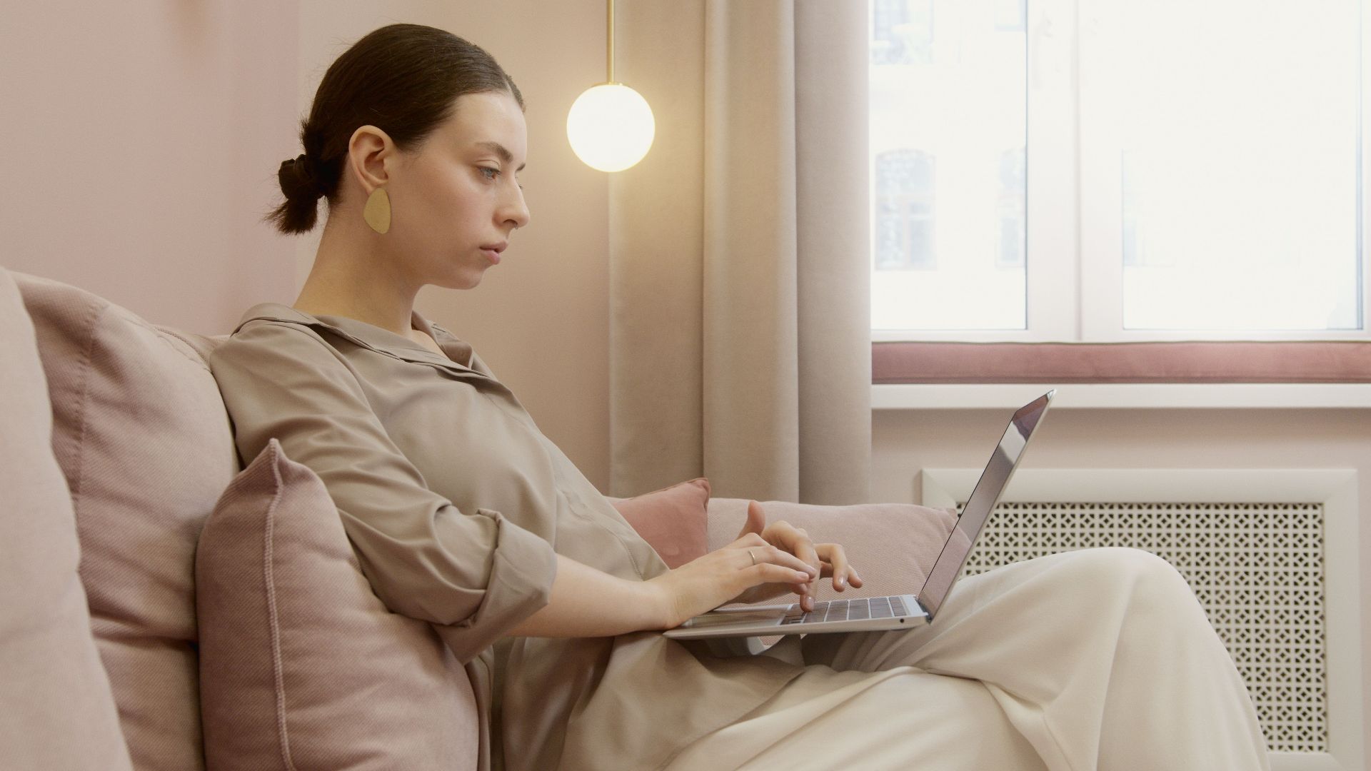 Stylish woman working remotely from her cozy living room, using a laptop.
