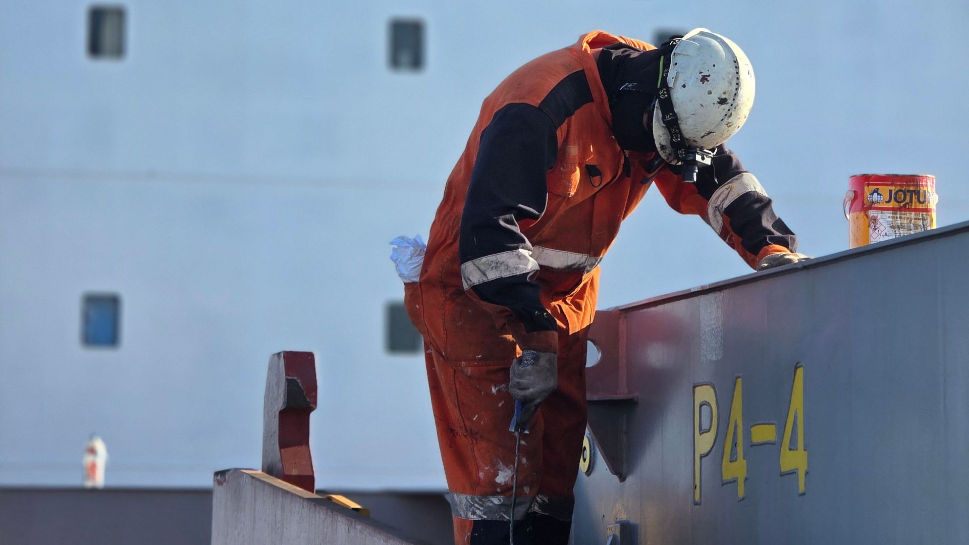 Ship worker performing maintenance under safety guidelines in Mozambique.