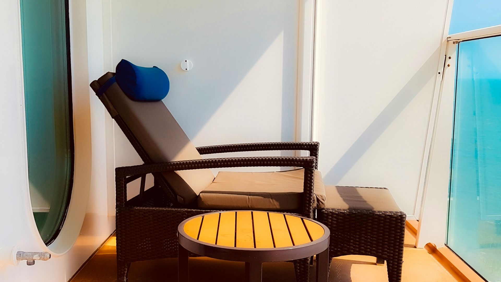 Sunny cruise ship balcony with lounge chair and round table