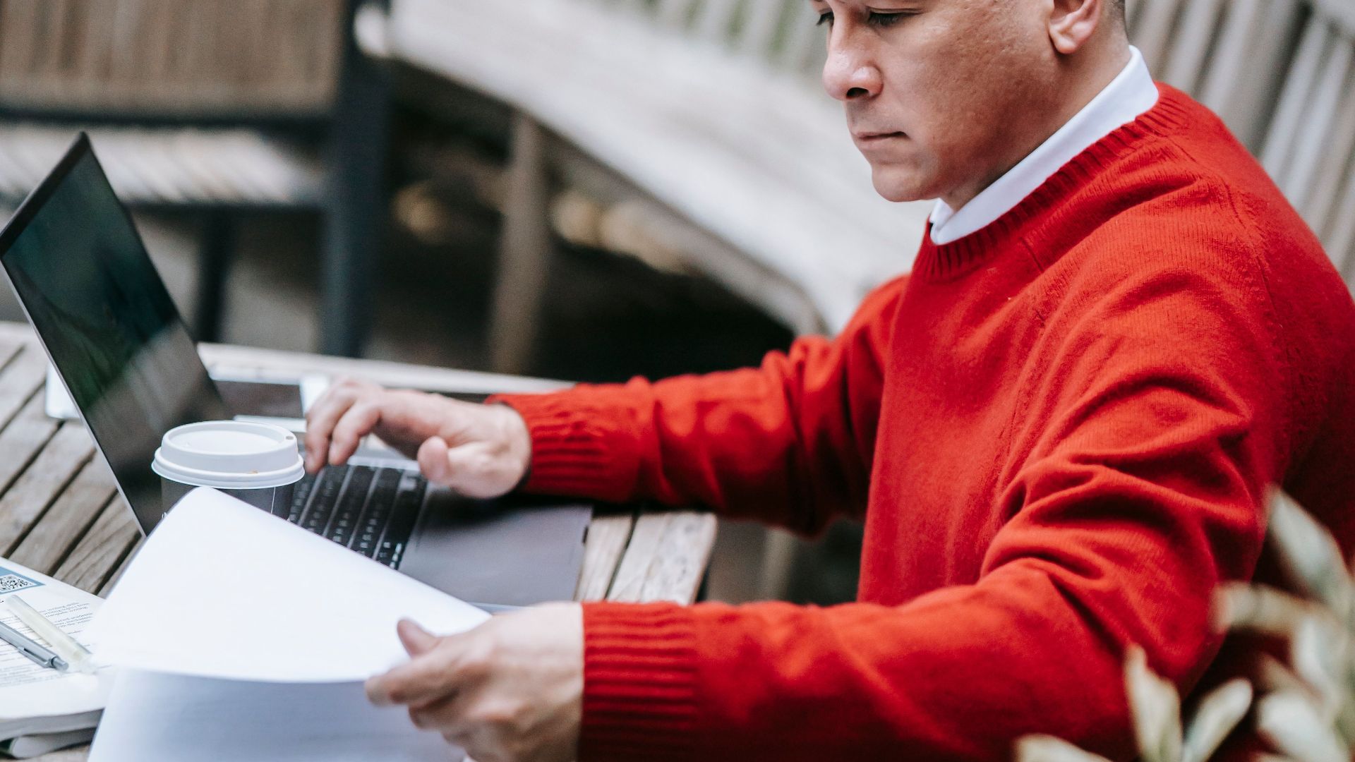 Businessman focused on remote work using a laptop in an outdoor setting.