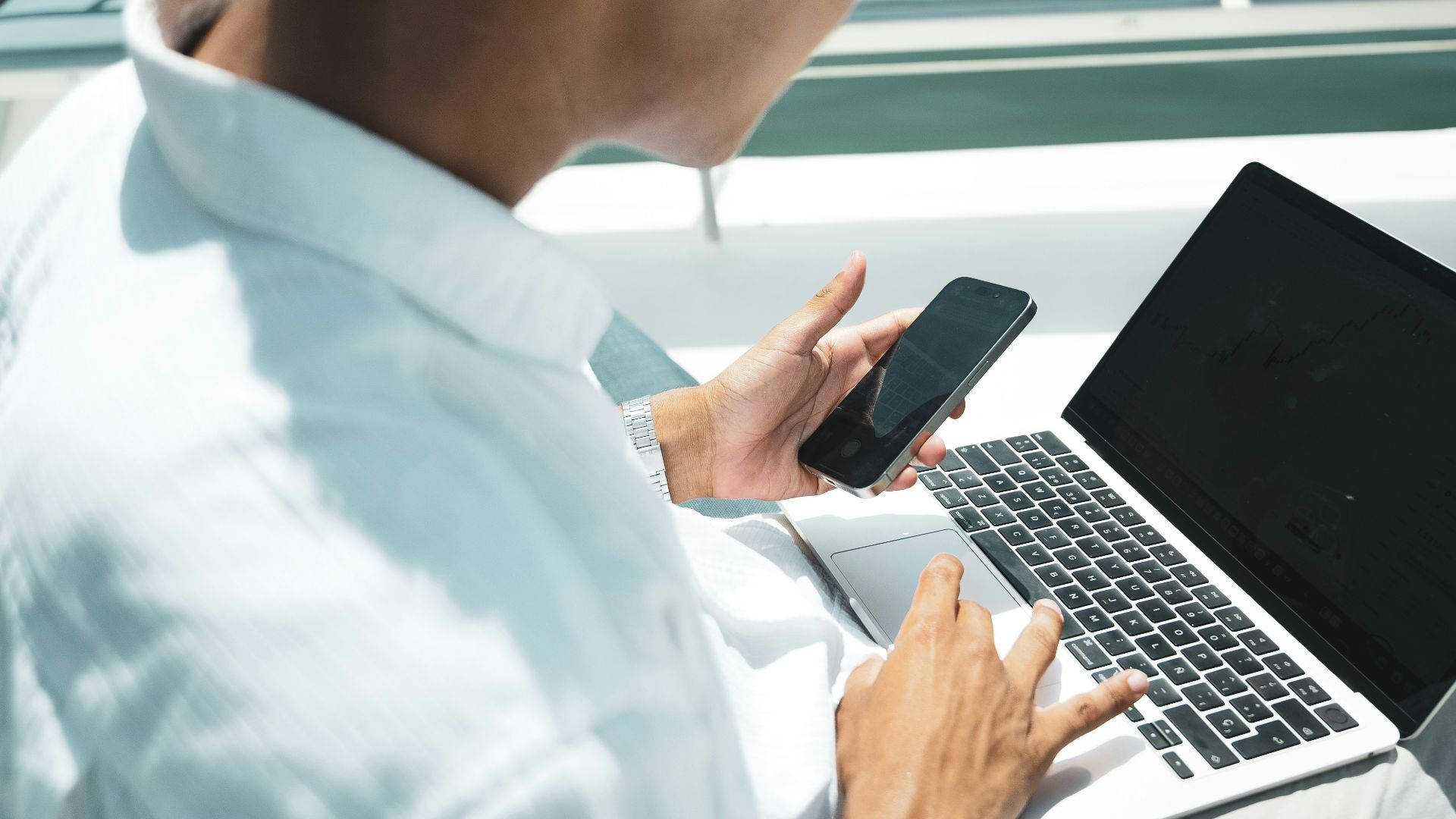 A man sitting on a bench using a laptop computer