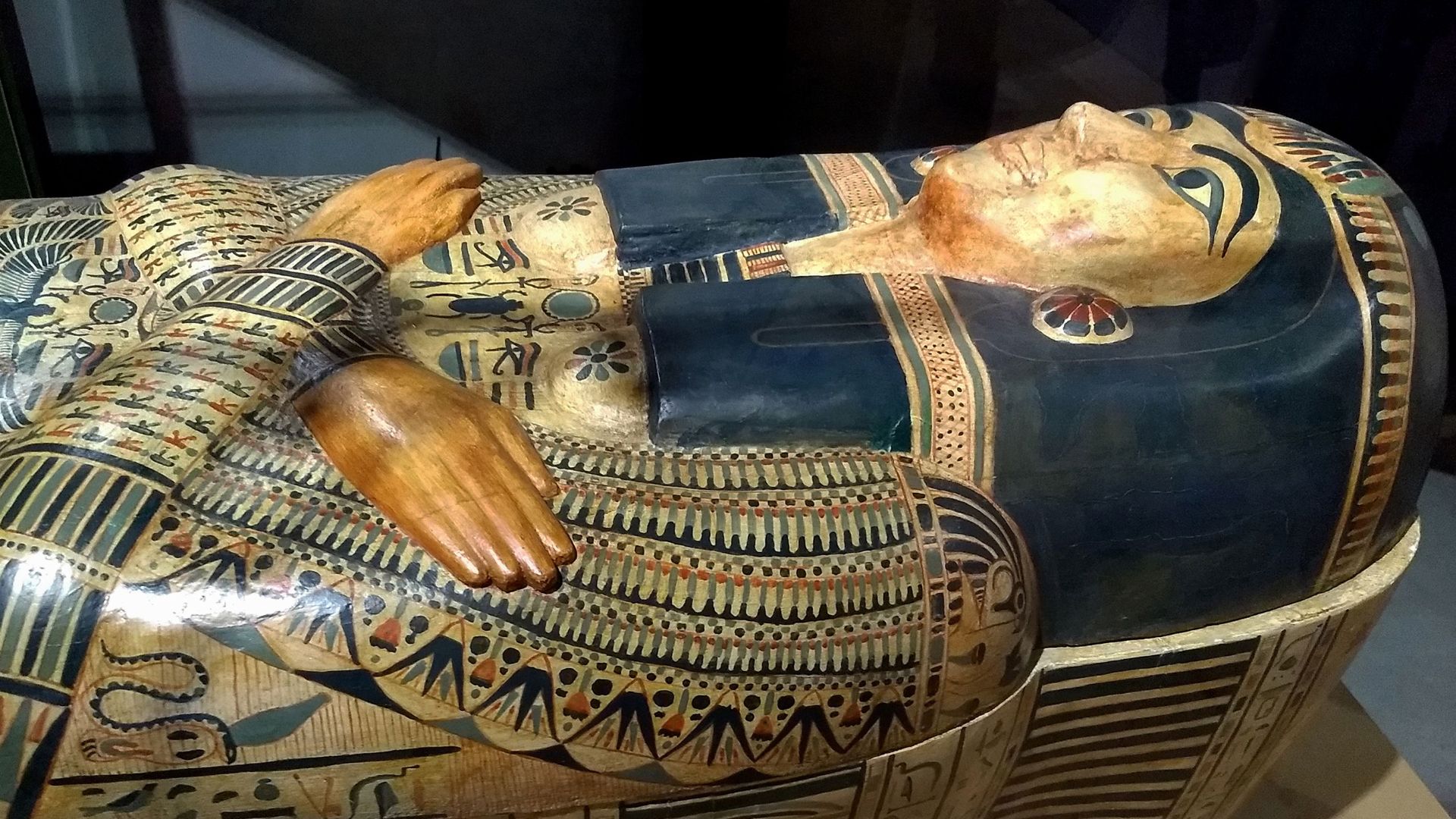 Ancient Egyptian sarcophagus with ornate hieroglyphs and patterns on display indoors.