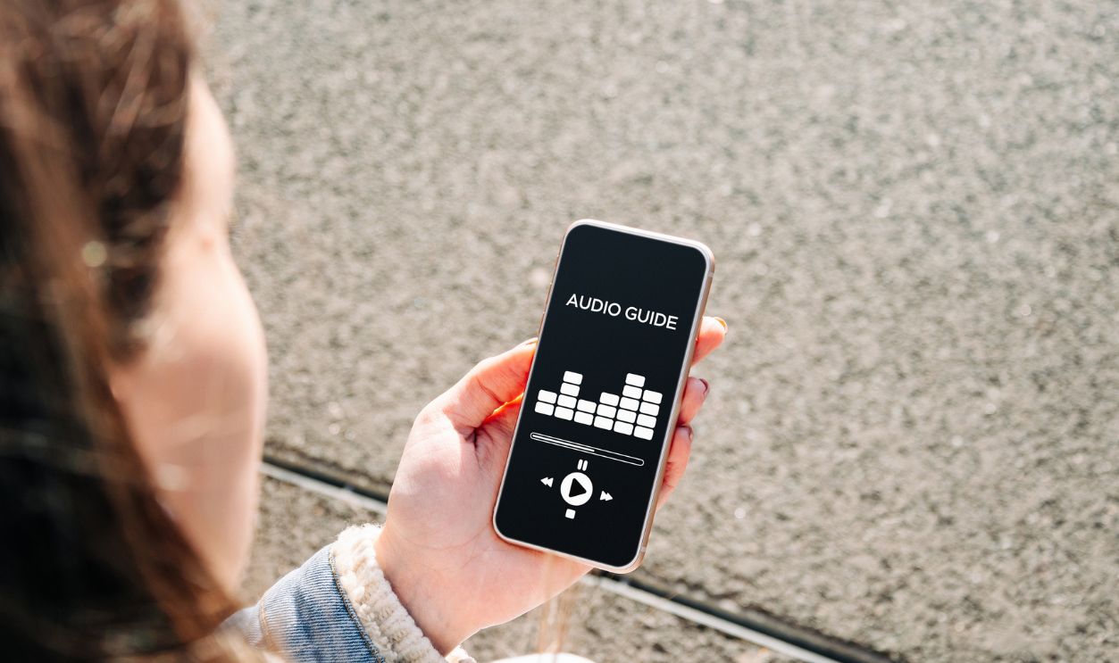 Audio tour guide online app on digital mobile smartphone. Happy young student woman holding phone listening audioguide. Digital library with audiobooks, podcasts, and courses