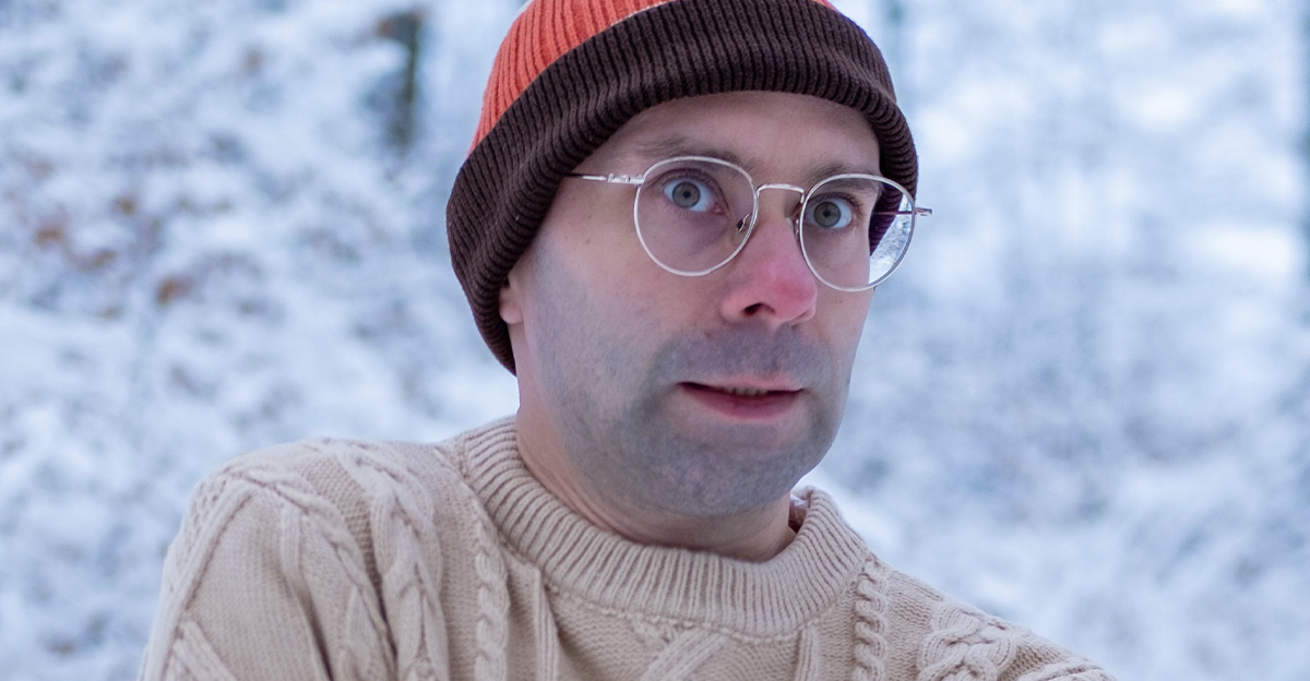Young man in beanie and sweater, shivering in the cold.