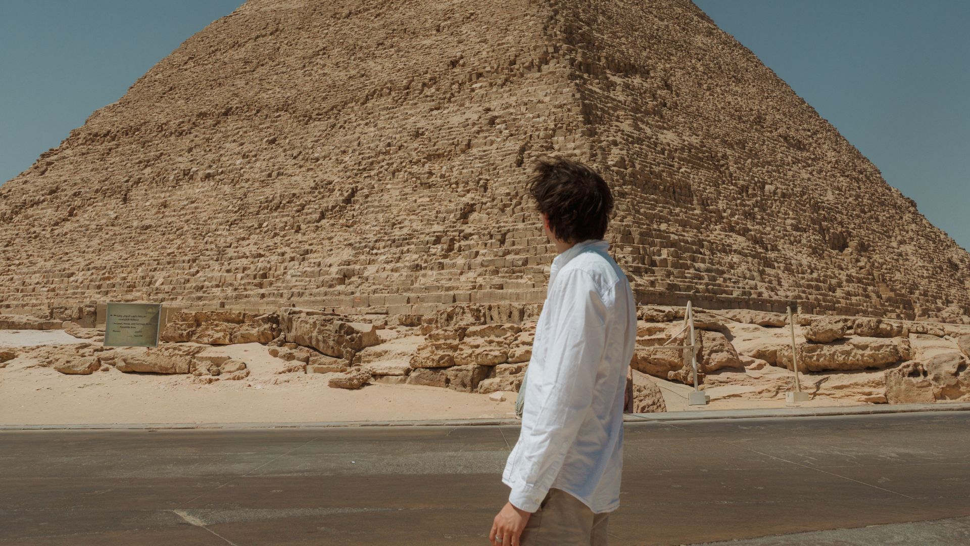 Man exploring the Pyramid of Khufu in Egypt under a clear blue sky.
