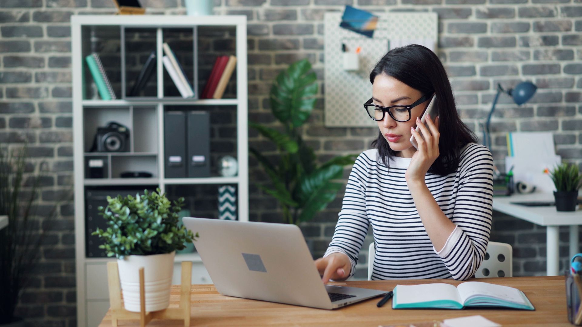 A woman working at her desk with laptop and phone, showcasing a modern office environment.