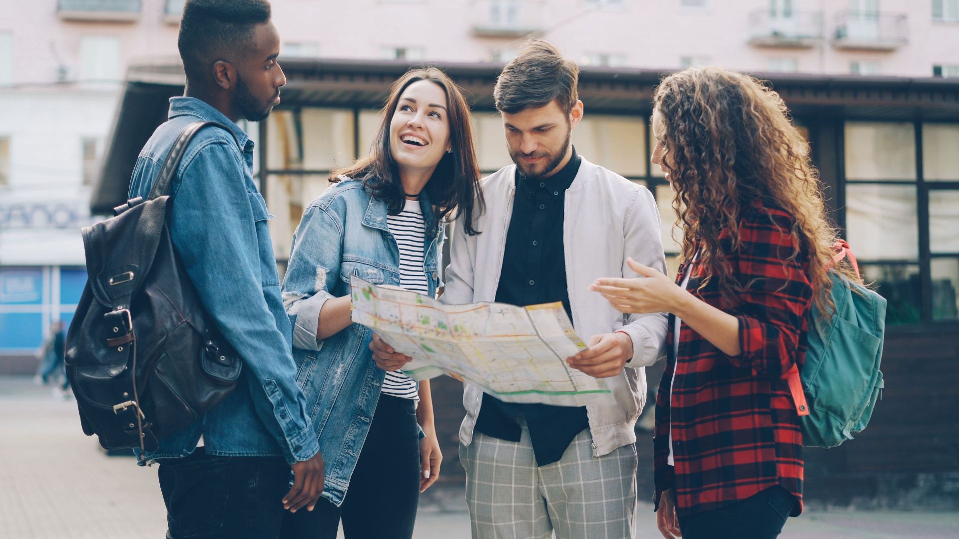 Four young friends reading a map outdoors, planning their city adventure.