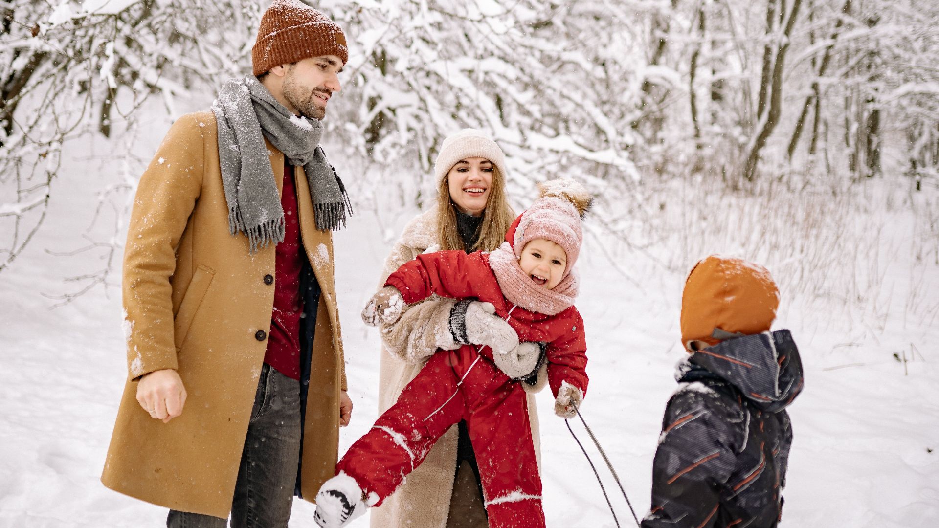 Happy family enjoying a snowy day in the winter woods, smiling and playing together.