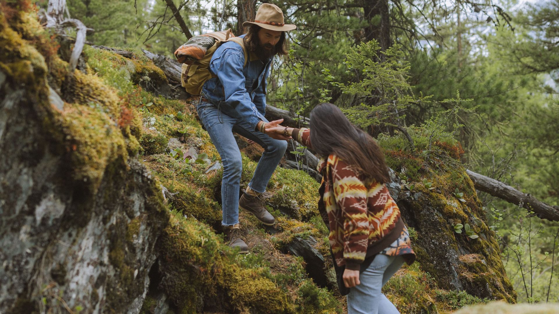 Two adults hiking through a lush forest, experiencing nature and adventure together.