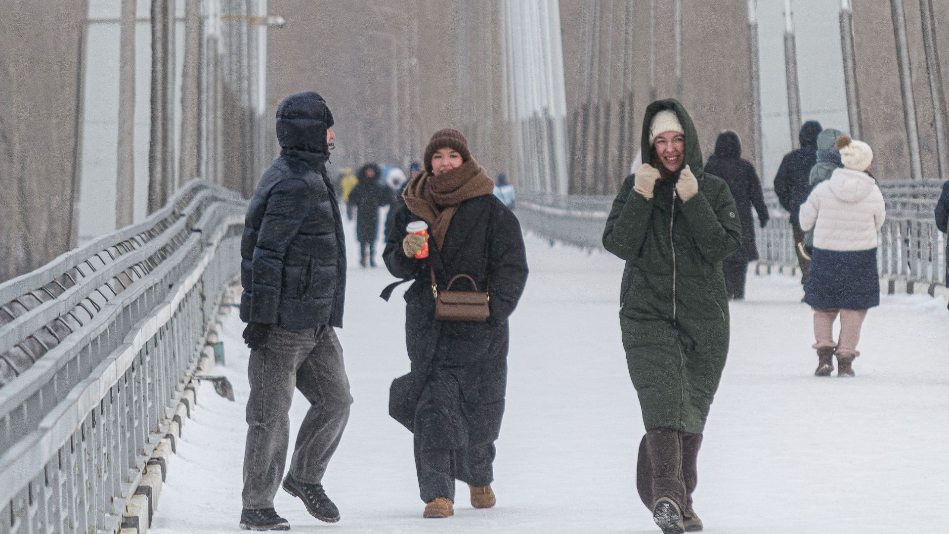 People bundled up against the cold walking on a snowy bridge in winter.