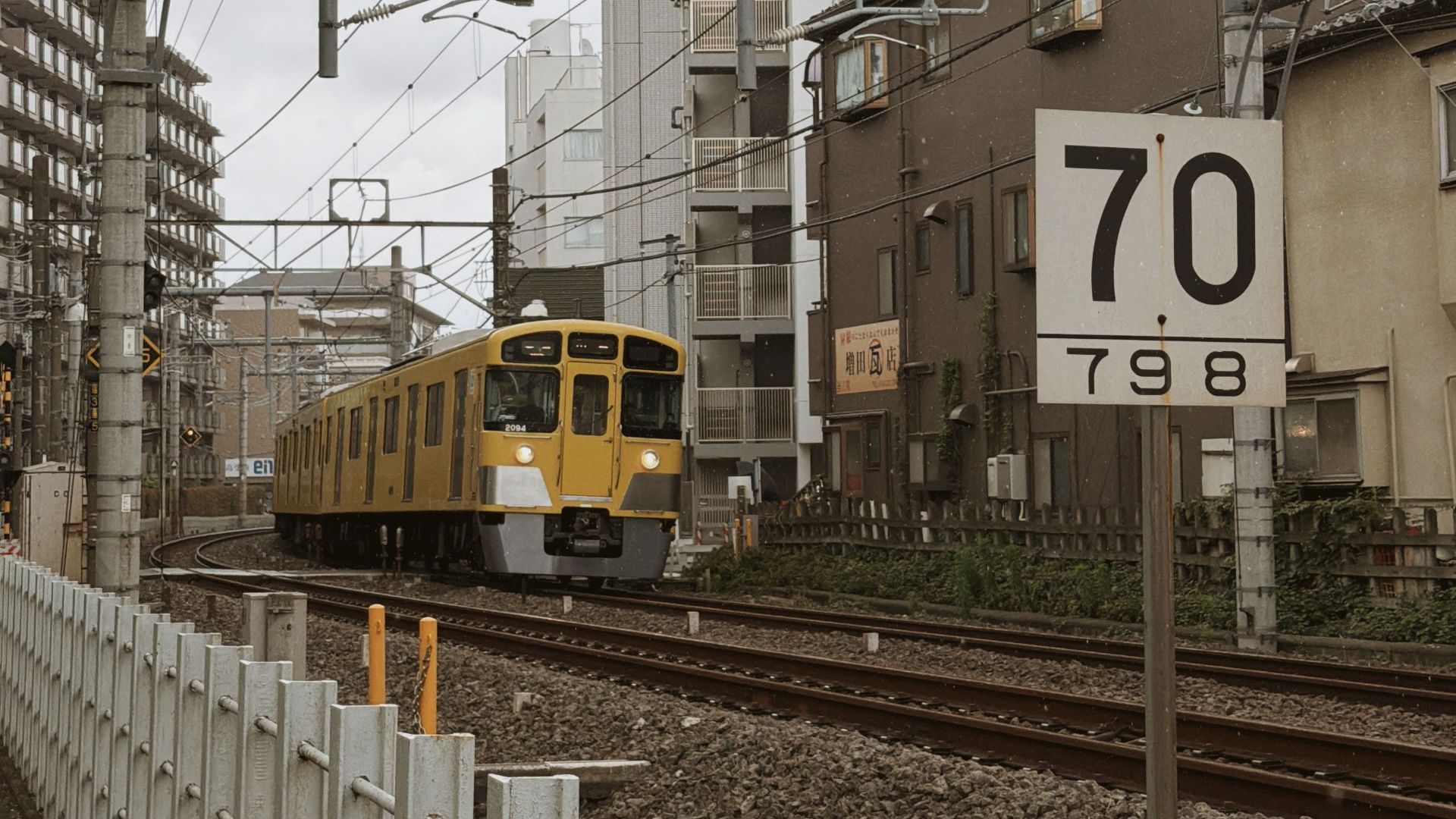 Yellow train passing through a residential area in Tokyo, Japan.