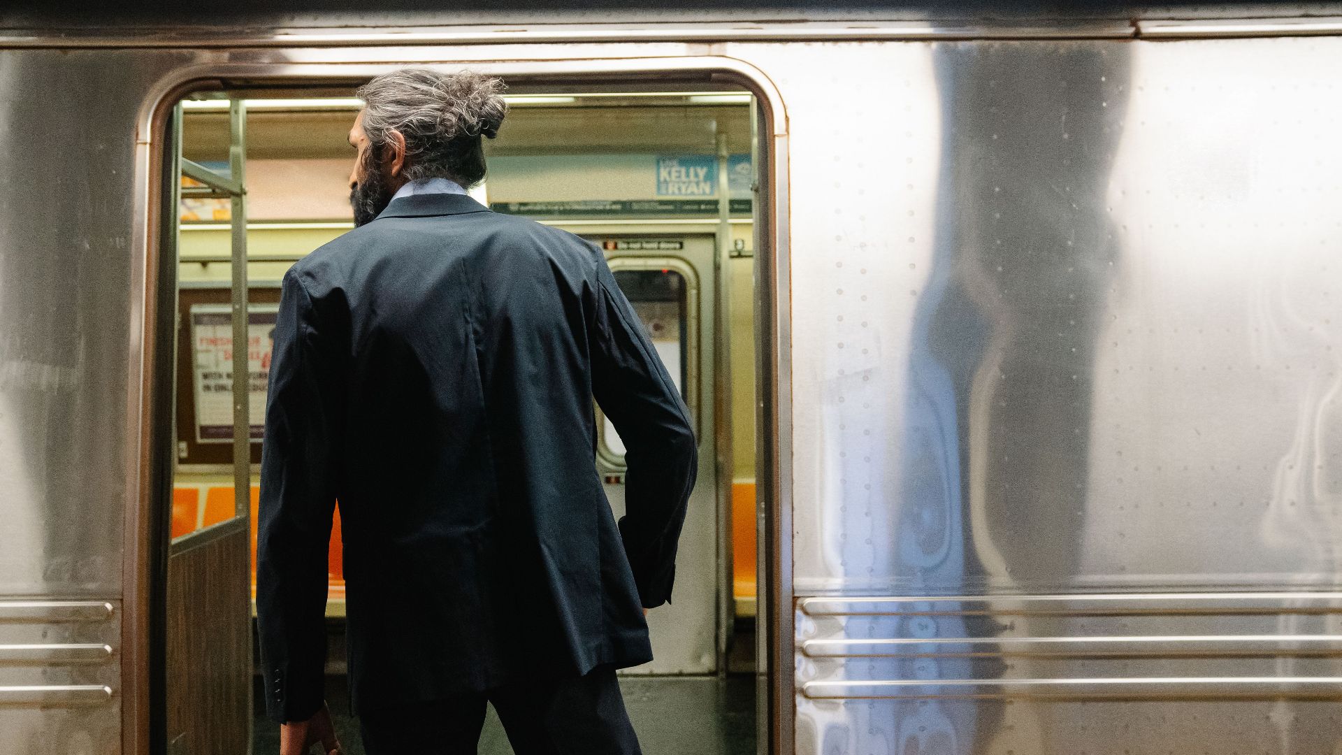 Back view of a businessman entering a subway train, symbolizing daily commute.