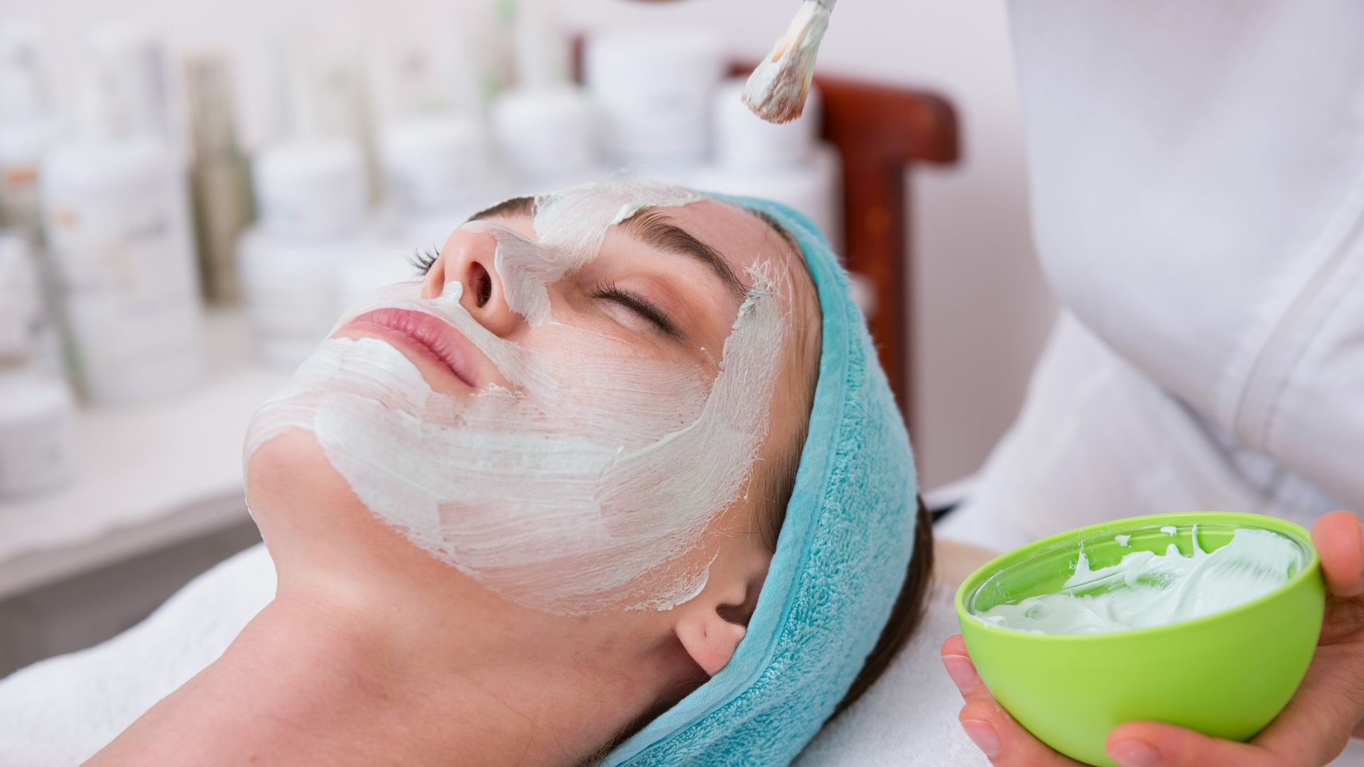 woman lying on blue towel with white cream on face
