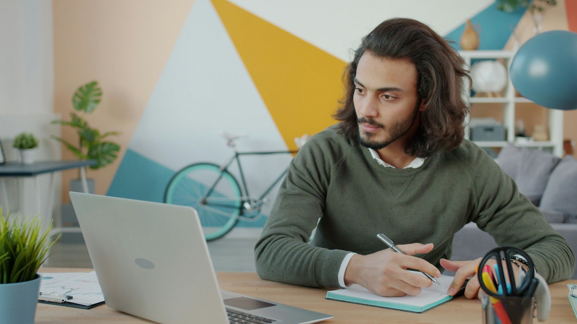 Man working at a desk with a laptop and notebook