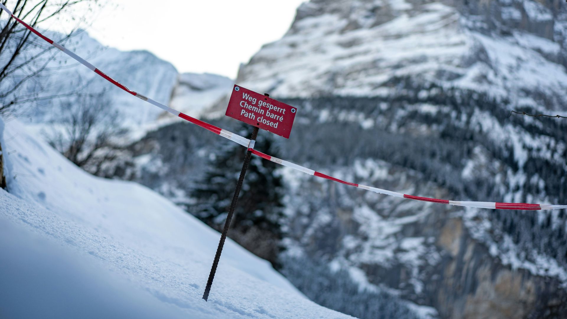 a red sign sitting on the side of a snow covered mountain