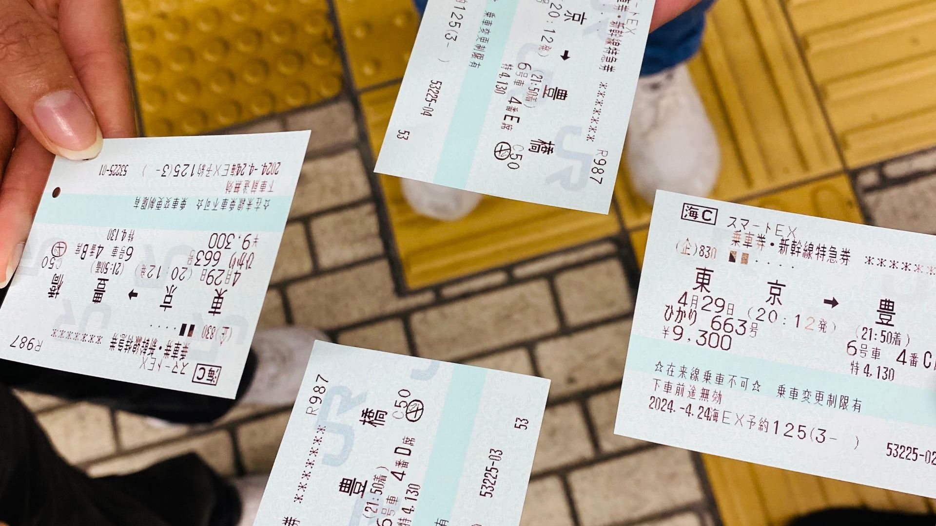 Four people holding train tickets at a Tokyo station, capturing a moment of travel.