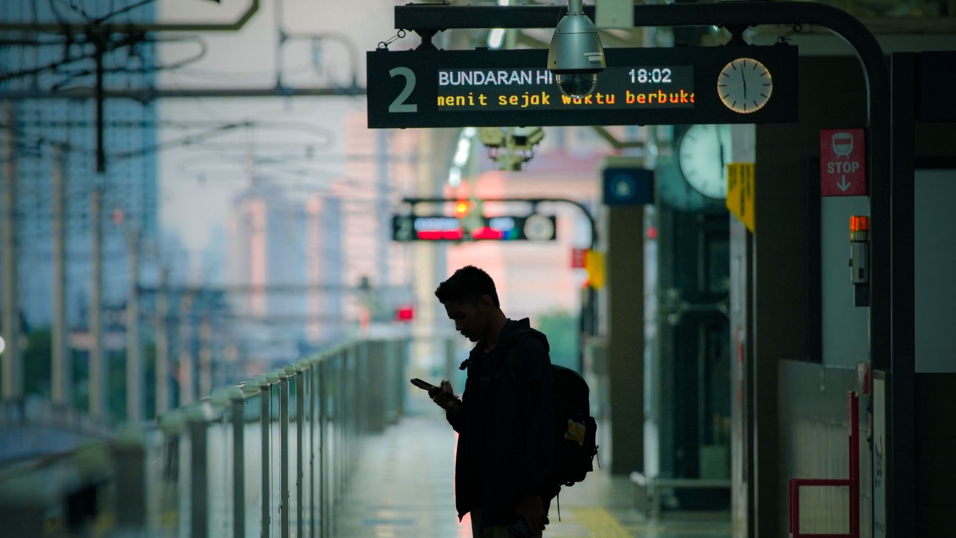 A silhouette of a man checking his phone at a railway station platform in Jakarta, Indonesia.