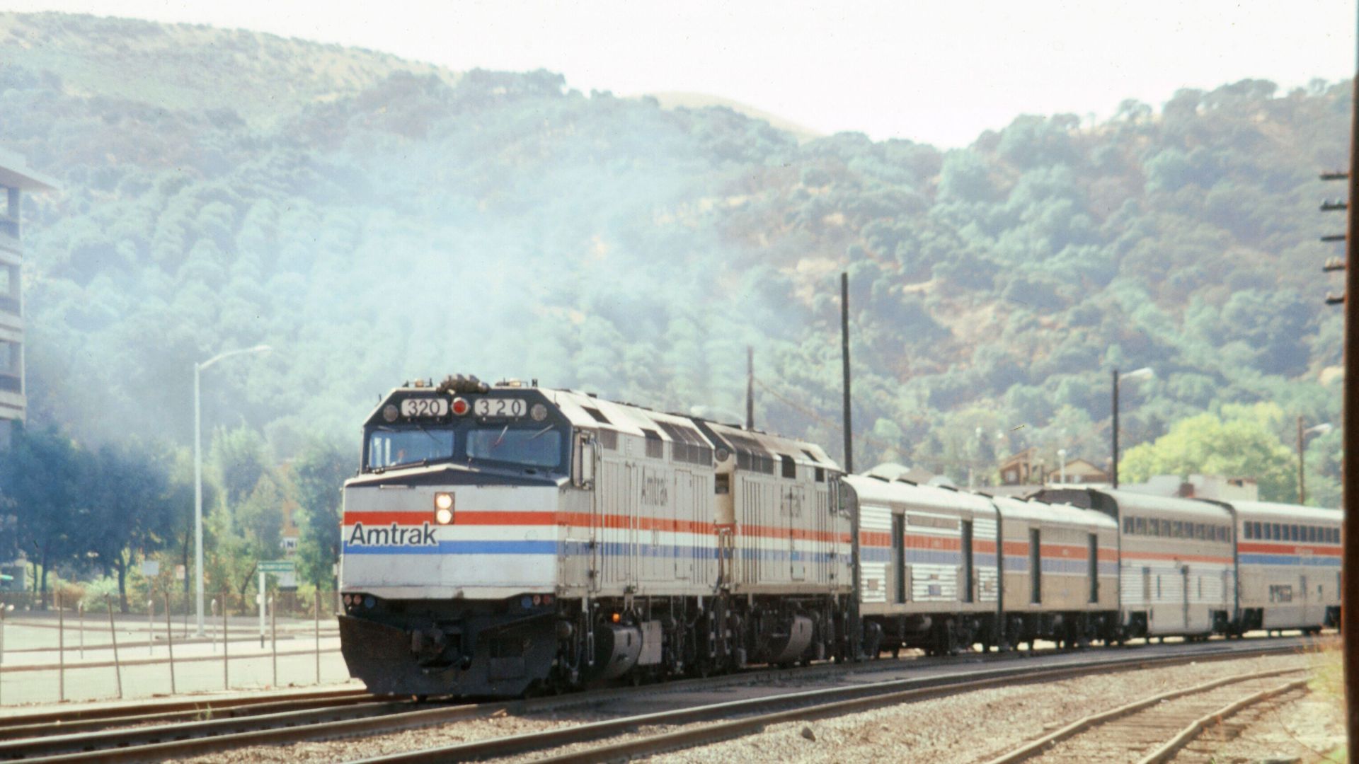 Amtrak train traveling through Martinez with picturesque hills in the background.
