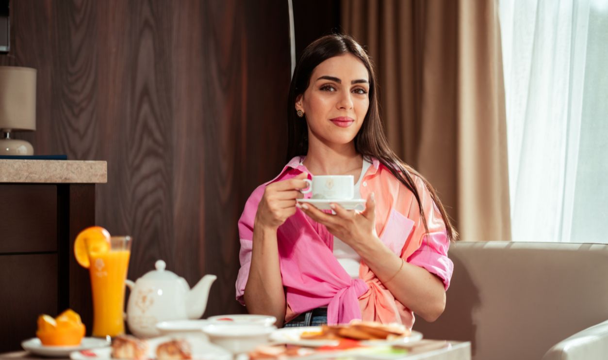 Woman enjoying a leisurely breakfast indoors with tea and juice in Baghdad hotel
