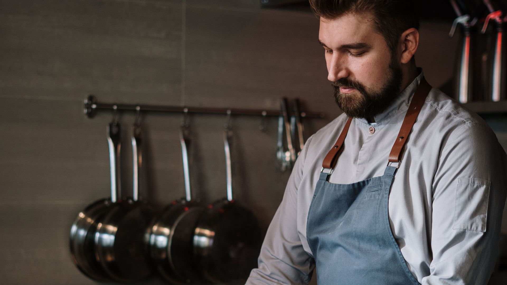 Chef in a modern kitchen cooking with stainless steel pots, showcasing culinary skills.