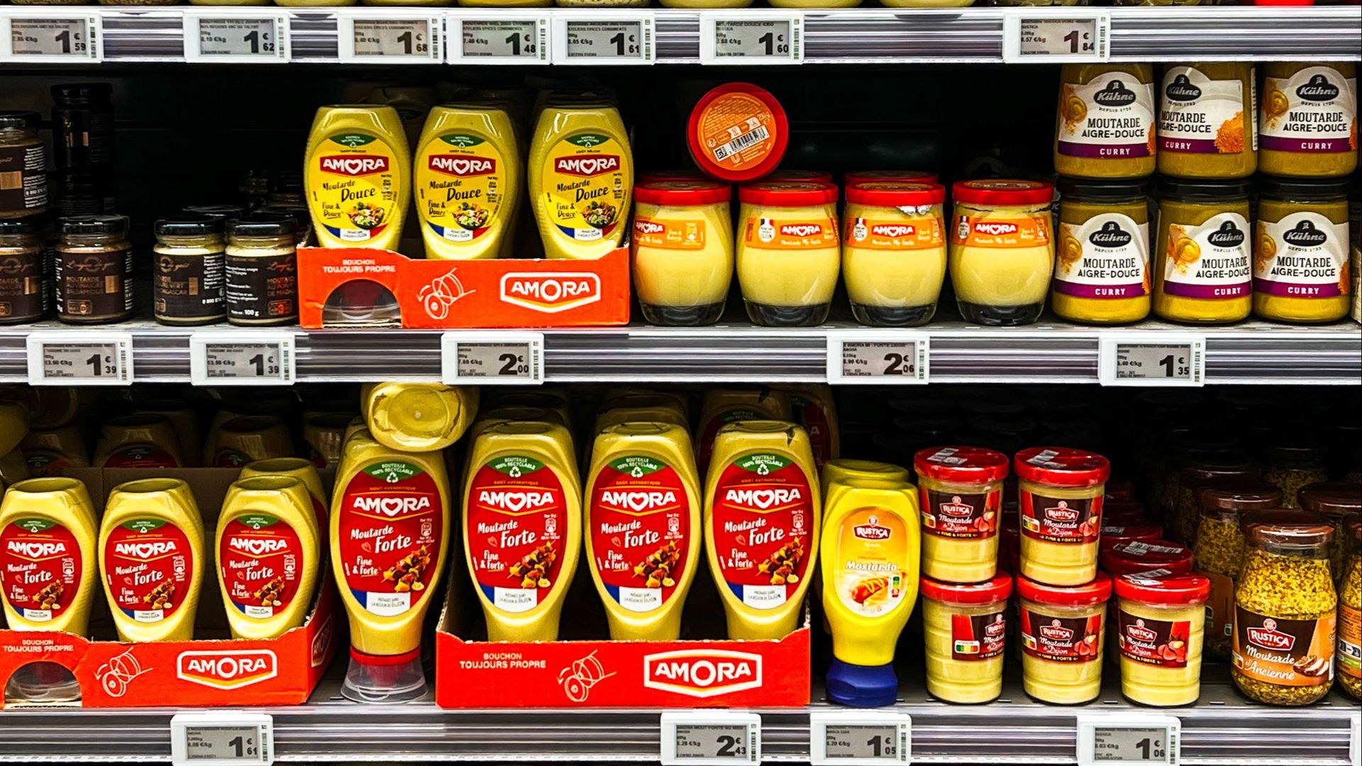 Colorful display of mustard jars on a supermarket shelf in Calais, France, showcasing variety and choice.