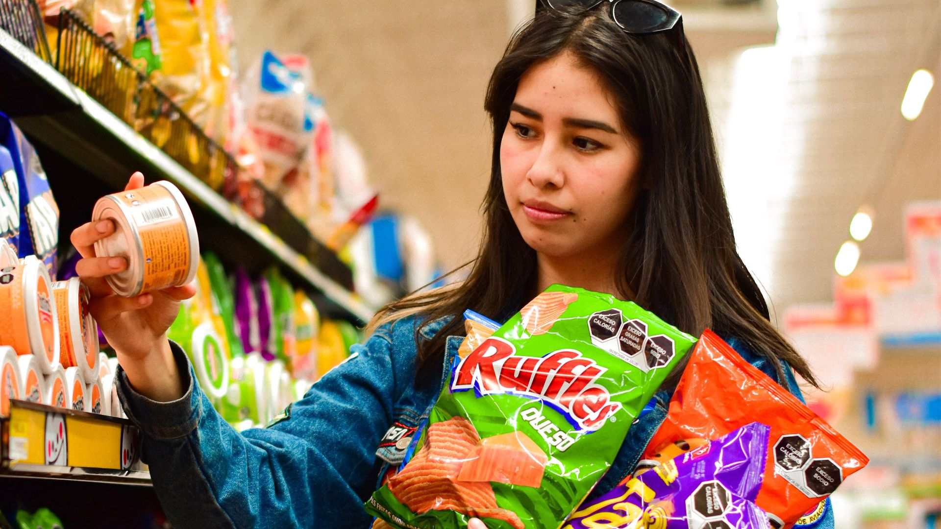 Woman selecting crisps in Texcoco, Mexico supermarket aisle.